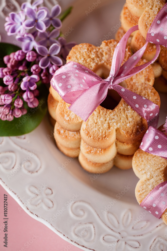 Butter cookies with pink ribbon and lilac flowers, top view Butter cookies with pink ribbon and lilac flowers, top view