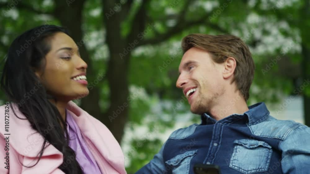 Attractive mixed ethnicity couple on a date, talking and flirting in the park Attractive mixed ethnicity couple on a date, talking and flirting in the park