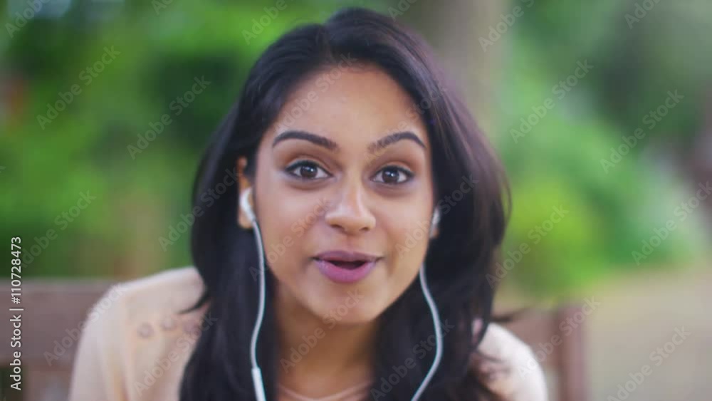  Attractive young Asian woman sitting in the garden making a video call