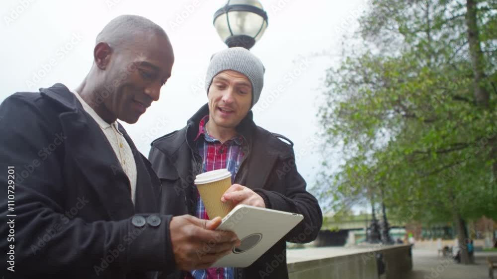  Happy casual male friends hanging out in the city with computer tablet