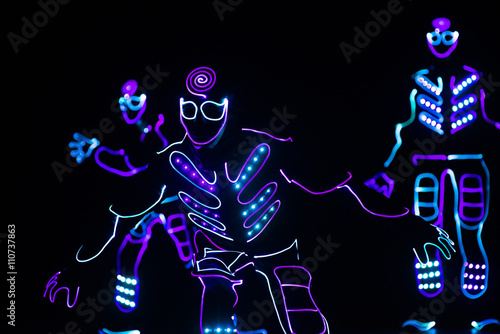 dancers in led suits on dark background, colored show