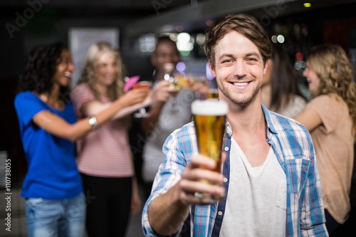Smiling man showing a beer with his friends