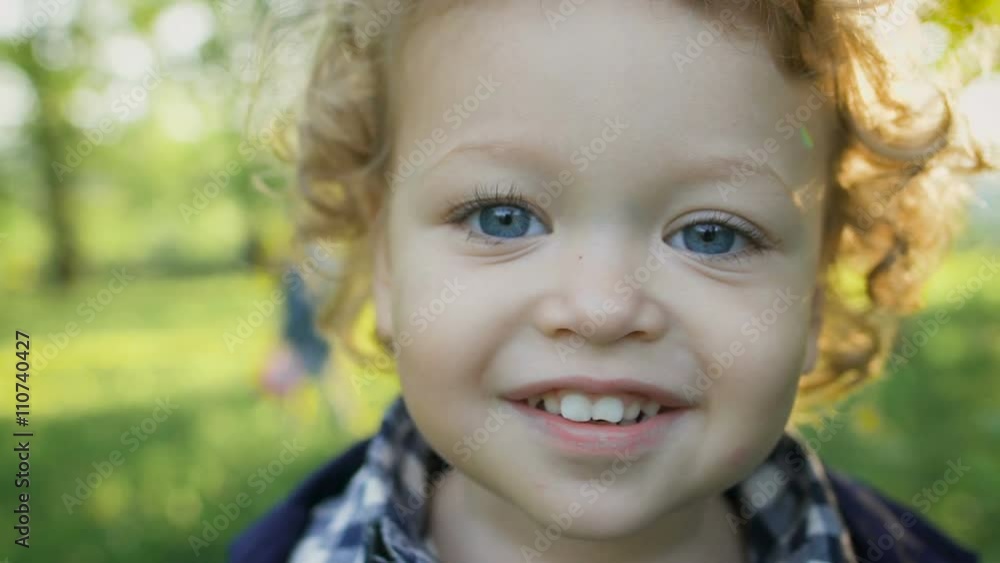 Portrait of a happy boy in the park malenkovo. Curious children with curly blond hair and blue eyes. Portrait of a happy boy in the park malenkovo. Curious children with curly blond hair and blue eyes.