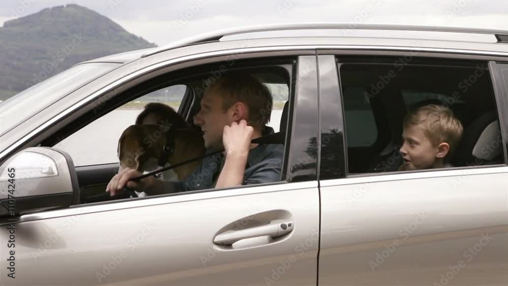 Mother, father, son and beagle dog sitting in the car, fastening belts and move off to the trip Mother, father, son and beagle dog sitting in the car, fastening belts and move off to the trip