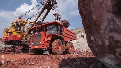 Excavator loads ore into dump-truck. 