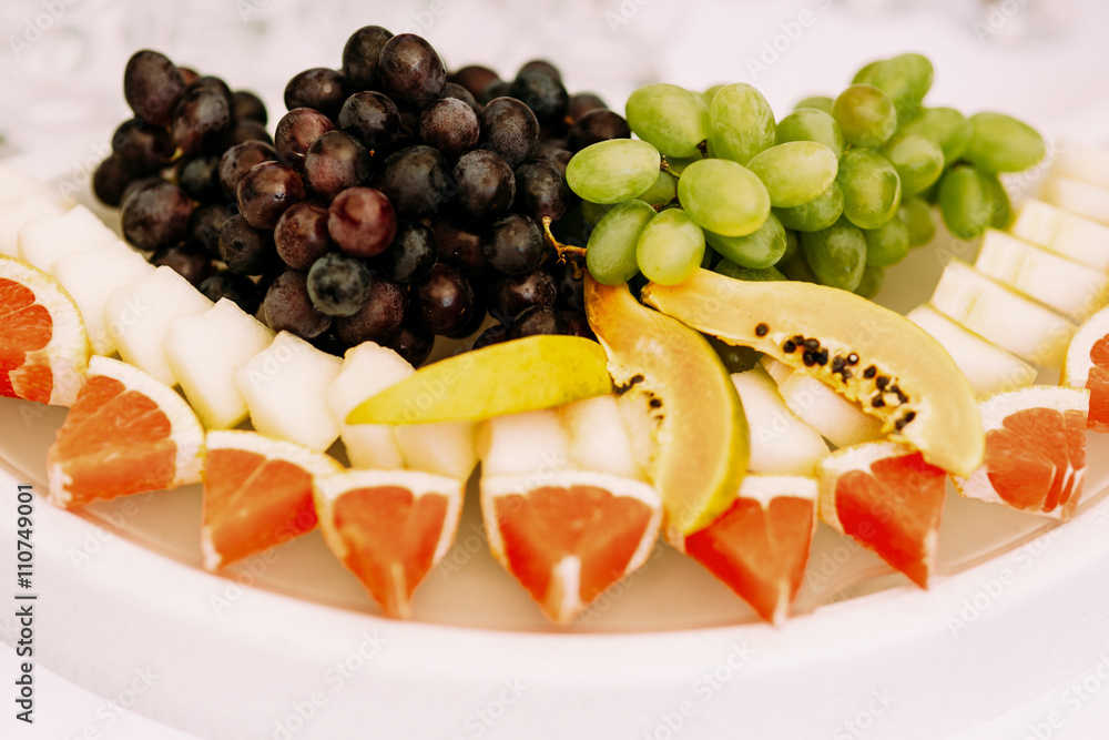 Grapes oranges and other fruits on the plate Grapes oranges and other fruits on the plate