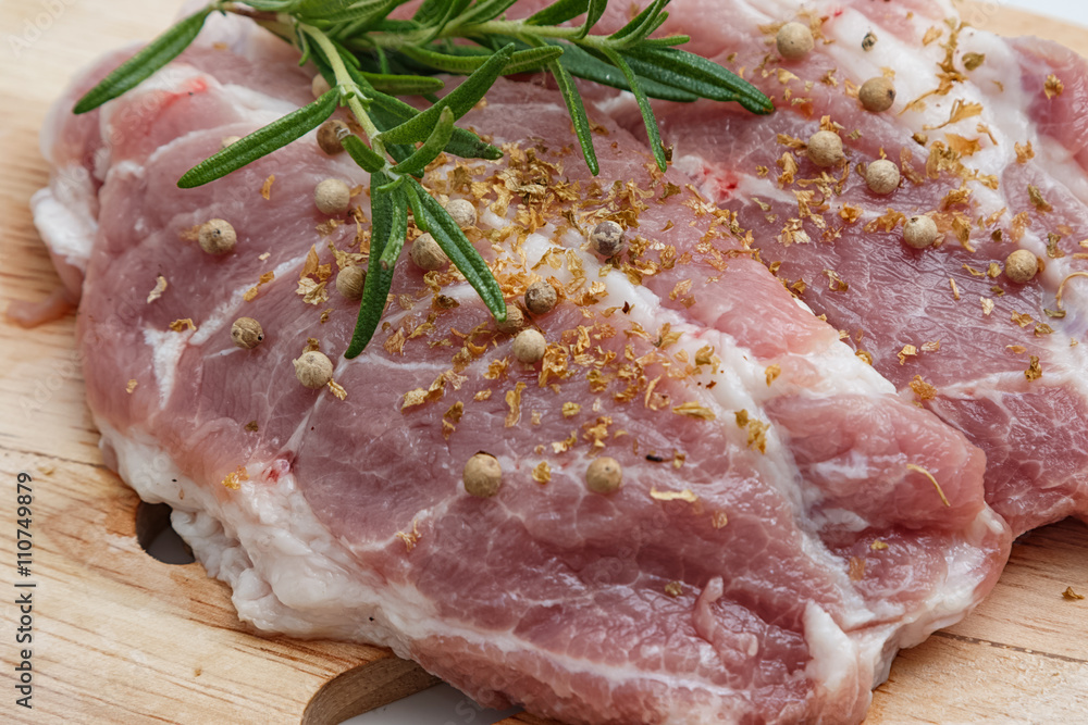 Closeup raw pork meat on cutting board with herbs