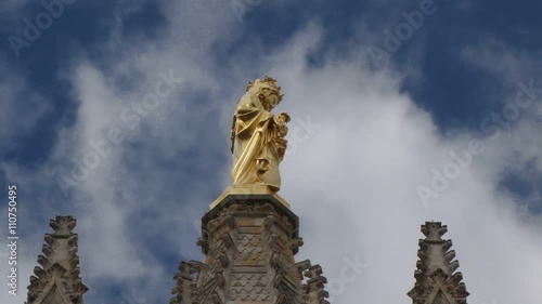 Statue of the Virgin Mary on top of the Pey Berland Tower in Bordeaux Cathedral. Clouds flot past in the background photo