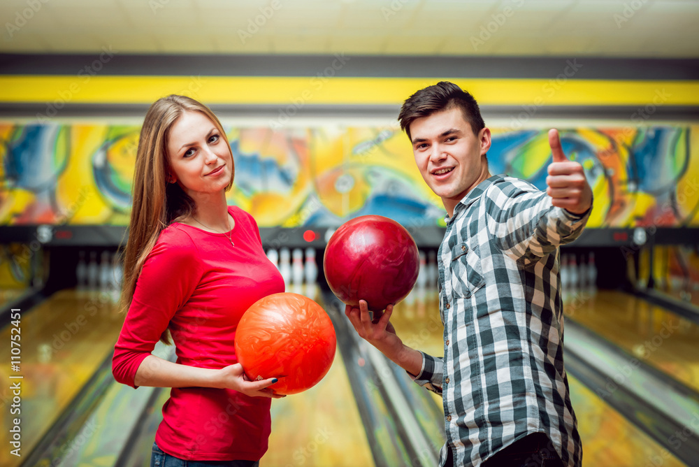 Fototapeta premium Beautiful girl and young man at the bowling alley