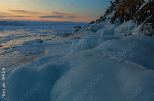 Huge icicles near rocks at sunrise.