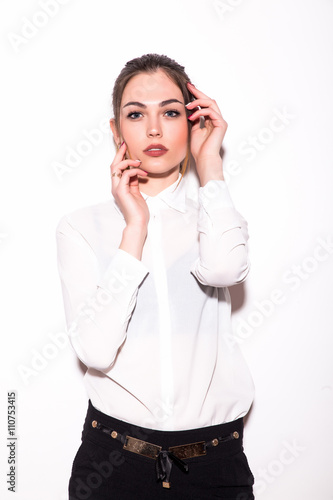 Beautiful young woman posing and looking at camera while standing against white background