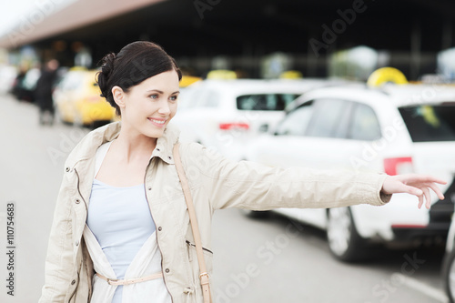 smiling young woman waving hand and catching taxi