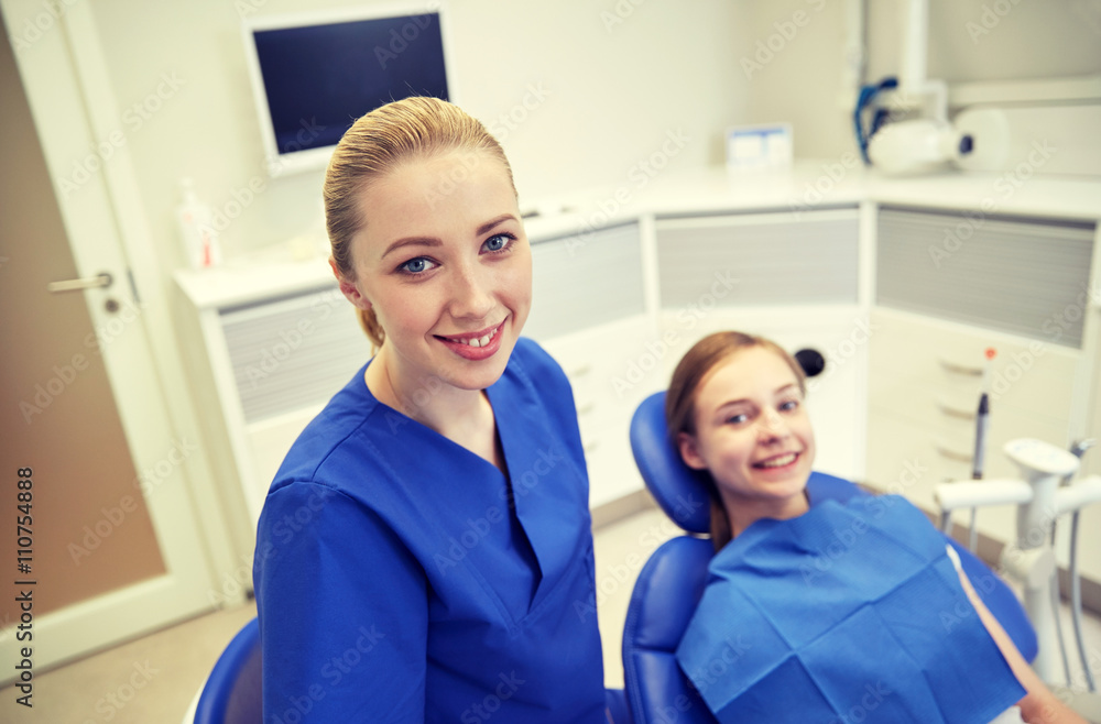 happy female dentist with patient girl at clinic happy female dentist with patient girl at clinic