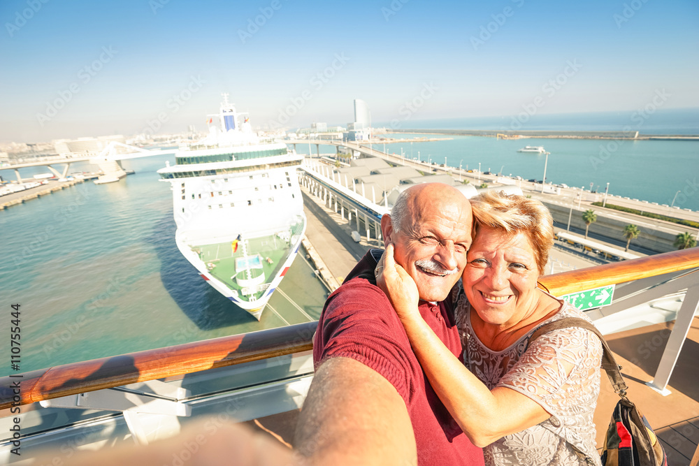 Senior happy couple taking selfie on cruise ship travel at Barcelona harbour - Active retired people having fun - obrazy, fototapety, plakaty 