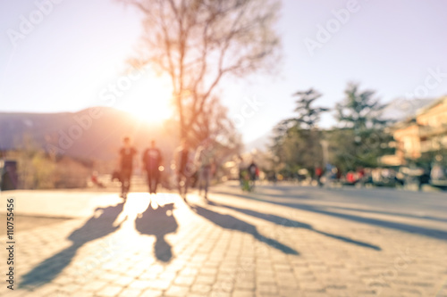 Blurred defocused silhouettes of four people walking on Meran street 