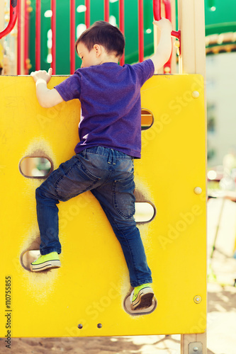 happy little boy climbing on children playground