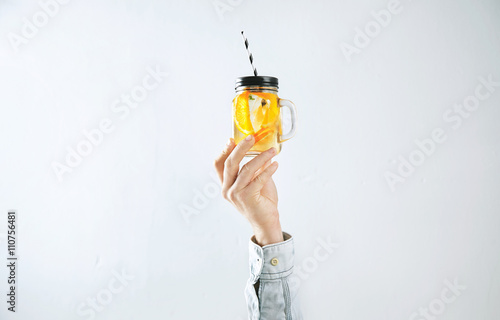 Men hand presents homemade cold lemonade from oranges, sparkling water and ice cubes isolated on white. Refreshment healthy cold drink in summer time