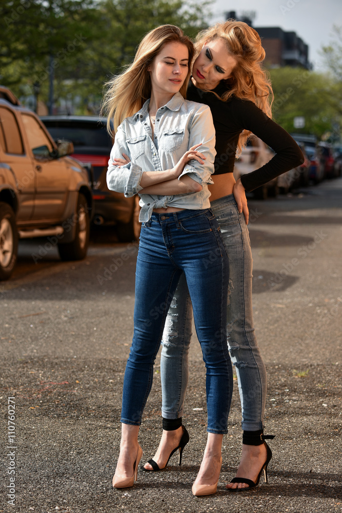 Two girls posing sexy wearing jeans and hi-heels. Stock Photo | Adobe Stock