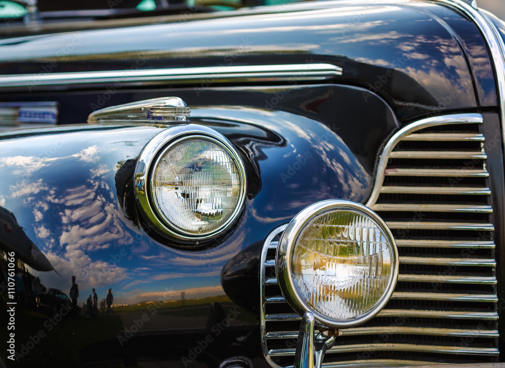 Close-up fragment of a black vintage car. Retro car. Headlights of vintage car. Selective focus.