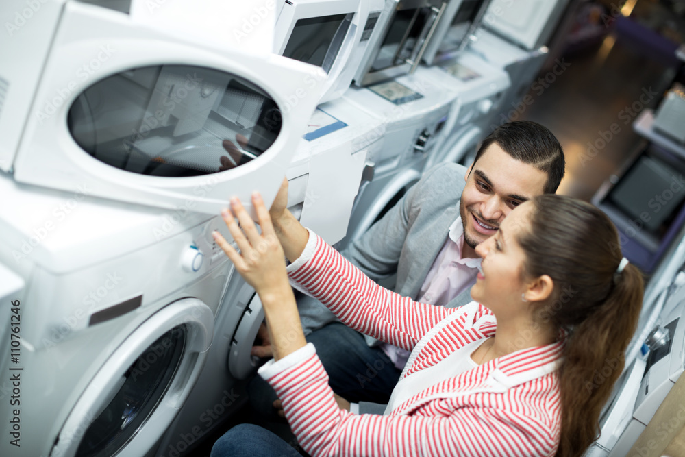 Fototapeta premium Happy family couple choosing new microwave