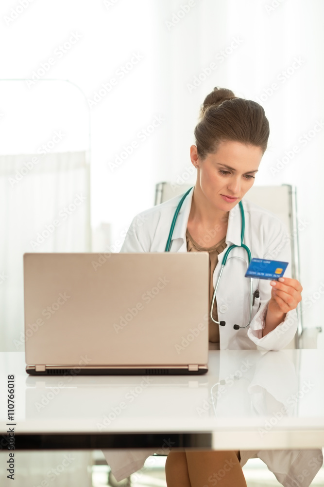 Female doctor with credit card shopping online in the office Female doctor with credit card shopping online in the office
