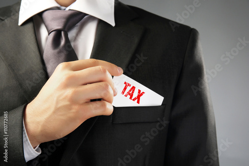 Tax Concept. Handsome businessman holding business card close up