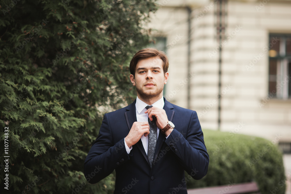 Young stylish businessman adjusting his suit, neck tie Young stylish businessman adjusting his suit, neck tie