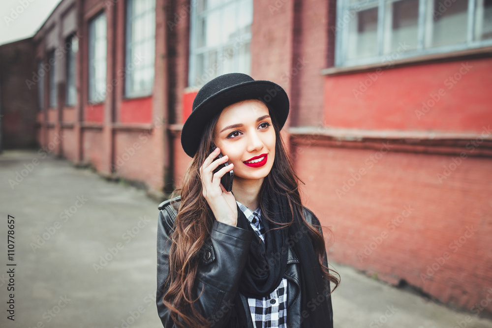 Young pretty girl in hat using smartphone.Woman using smart phone to make a call in the street Young pretty girl in hat using smartphone.Woman using smart phone to make a call in the street