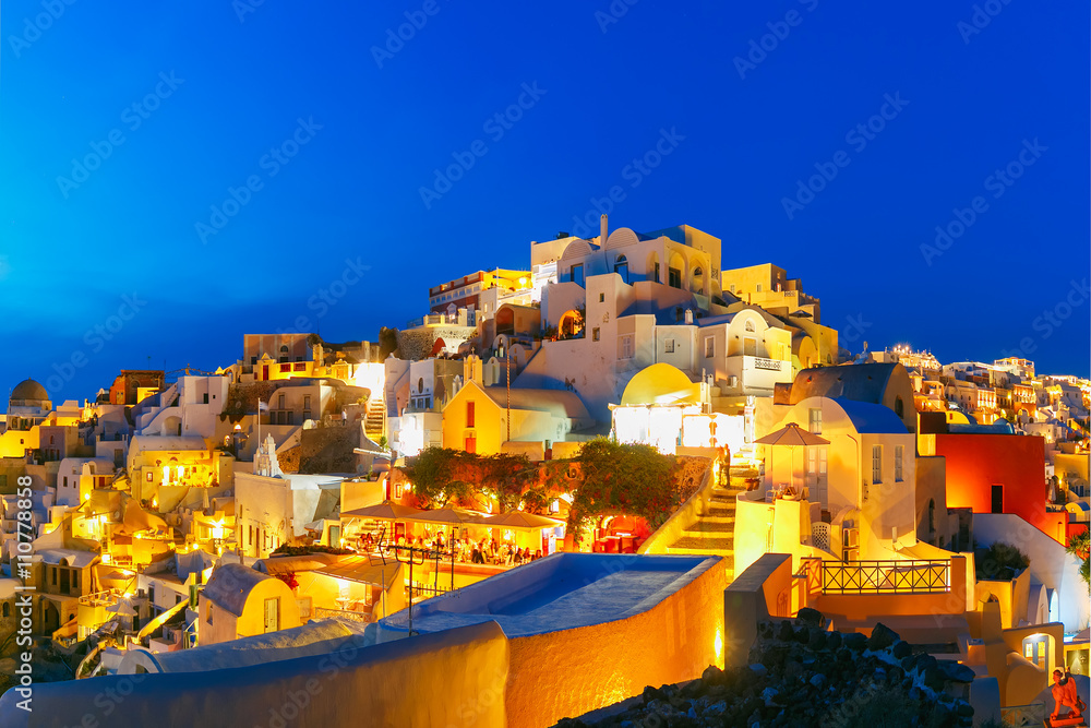 Old Town of Oia on the island Santorini, white houses and church with blue domes during twilight blue hour, Greece