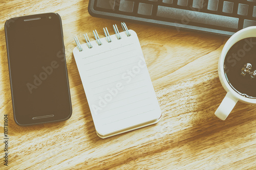 Office Table with Keyboard, mobile phone, notebook and cup of coffee