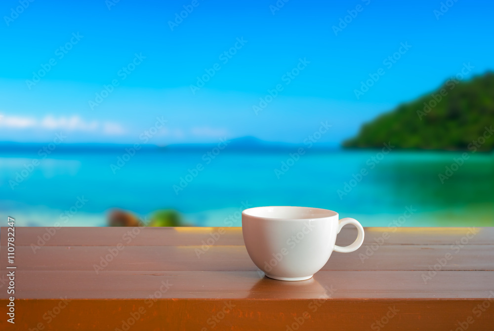 A cup on wooden table with blur sea background A cup on wooden table with blur sea background