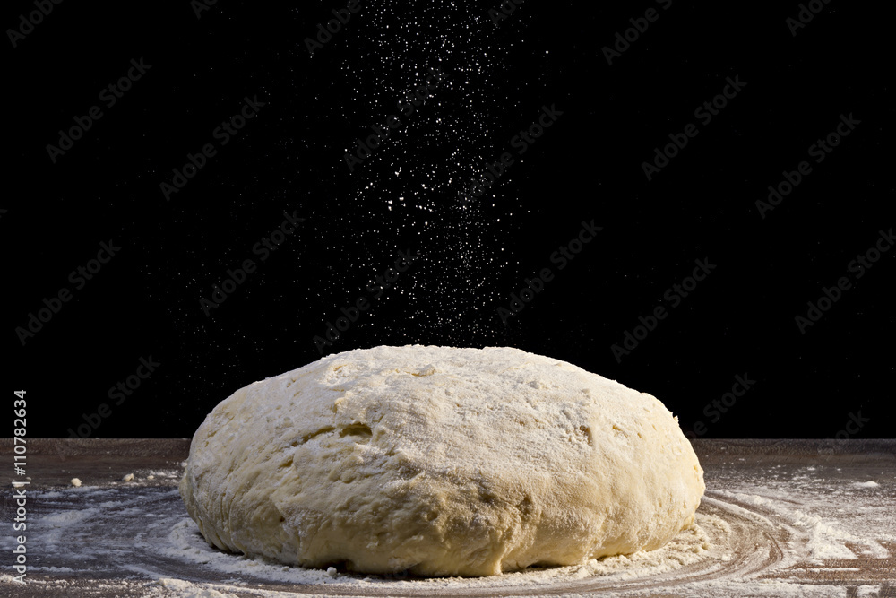 dough is sprinkled with flour on black background dough is sprinkled with flour on black background