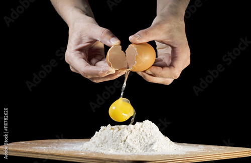 female hands breaking a raw egg