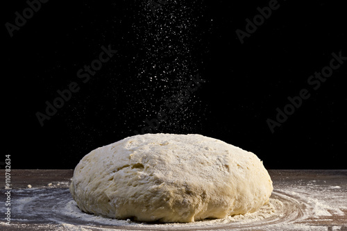 dough is sprinkled with flour on black background