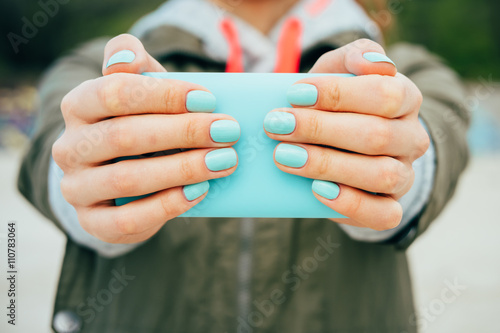 Female hands holding a mobile phone that is the same color as th