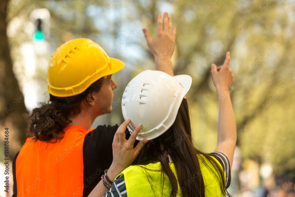 Back turned engineers, a boy and a girl both with long hair, pointing at something at construction site Back turned engineers, a boy and a girl both with long hair, pointing at something at construction site