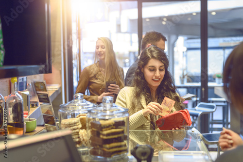 Foto Junge Frau bezahlt an der Kasse eines Bistros