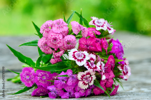 Bouquet of small carnations on a wooden background photo