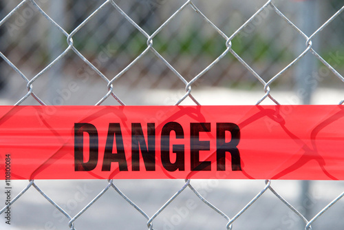 Red reflective danger barrier tape across a chain link fence photo