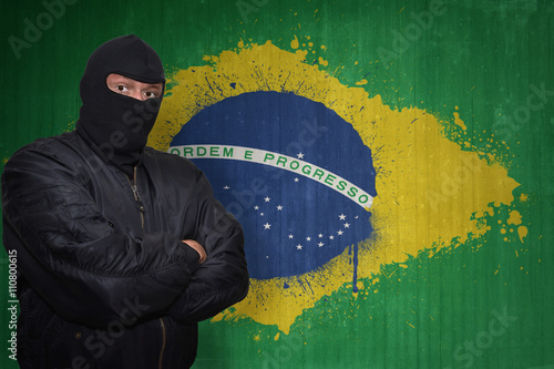 dangerous man in a mask standing near a wall with painted national flag of brazil photo