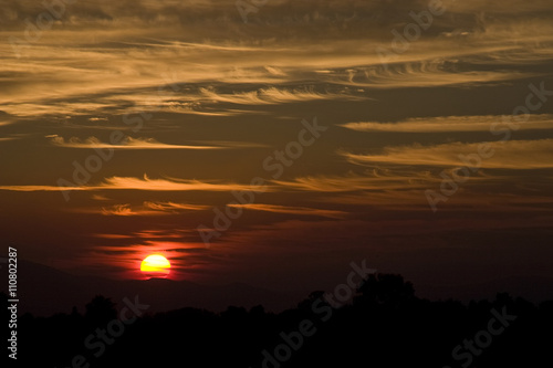 Crimson sunset, sun setting behind crest of mountain hill © sheilaf2002