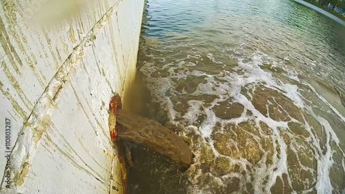 Dirty water flows from a pipe into the city river. The drain carries sewage