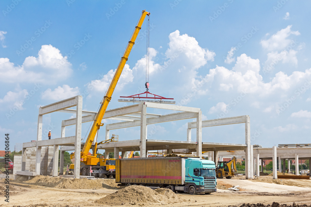 Mobile crane is unloading concrete joist from truck trailer.