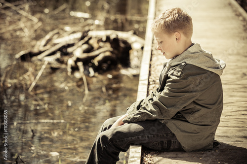 фотографія Single boy in jacket sitting on dock