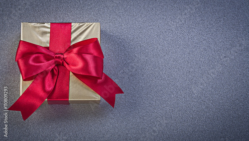 Present box wrapped in glittery paper on grey background holiday