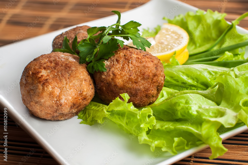 Meat patties in the plate with lettuce and parsley Meat patties in the plate with lettuce and parsley