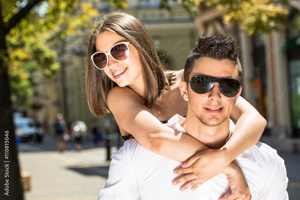 young couple having piggyback in summer in walking street young couple having piggyback in summer in walking street