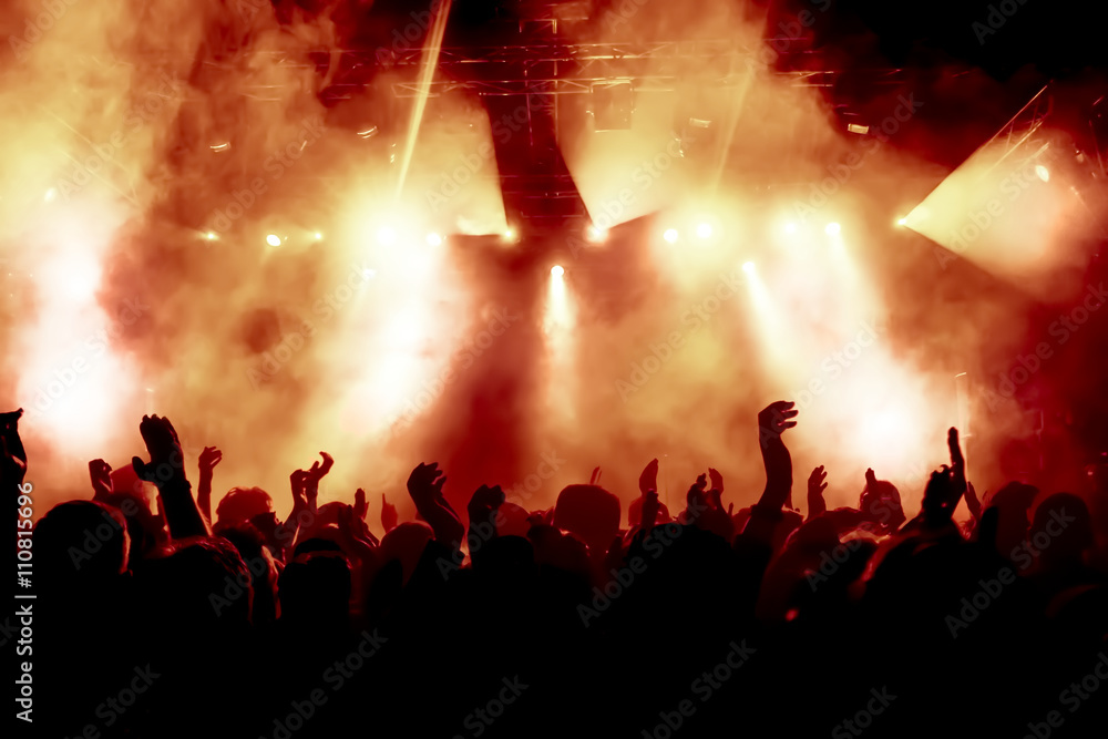 silhouettes of concert crowd in front of bright stage lights