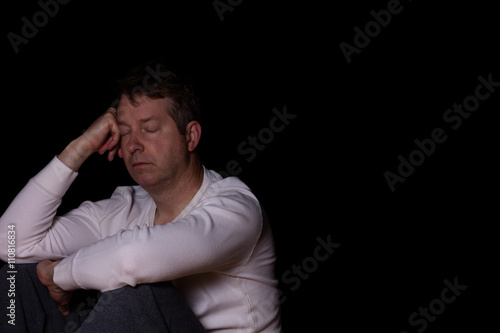 Depressed mature man thinking with his eyes closed in dark 