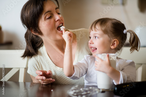 Obraz na plátně Licking of  whipping cream - mother with daughter